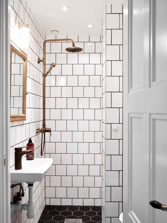 Bathroom with white tiles with black grout, apparent copper and wall-mounted sink