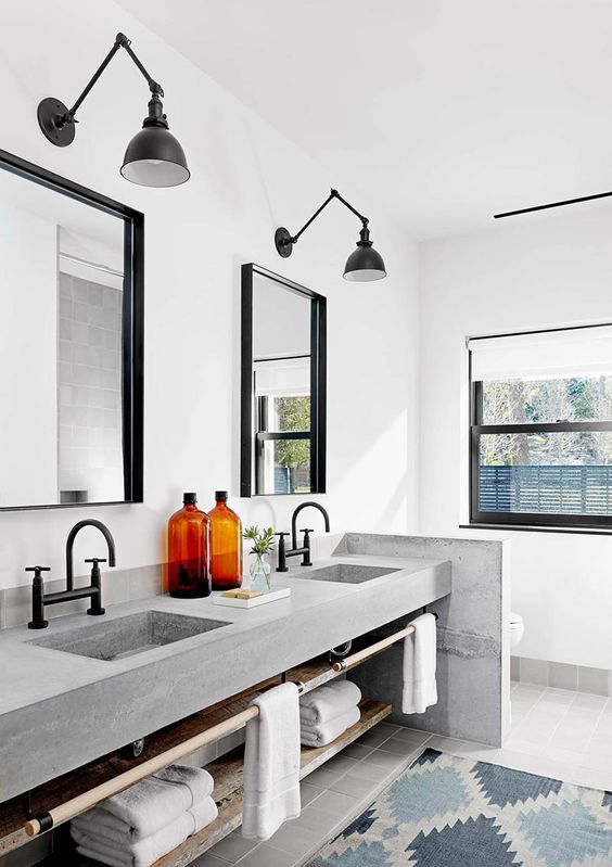 Black bridge faucets, mirror frames, lighting fixtures and window frames make a modern bathroom combined with concrete countertop and white walls.