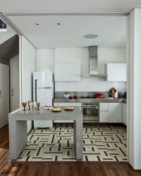 Kitchen separated from living room by island countertop and sliding doors. Tiles on the kitchen floor and hardwood flooring in the living room room. 