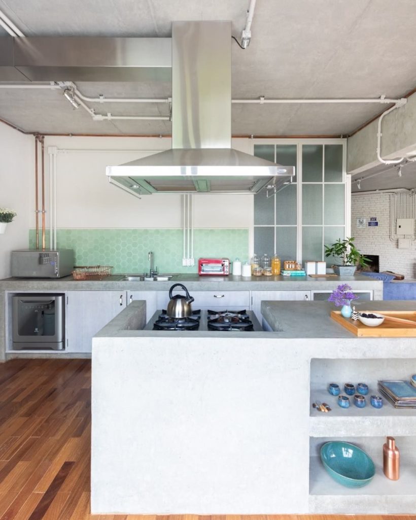 Range hood and stainless steel duct on apparent concrete slab. 